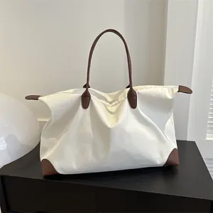 Large capacity minimalist travel tote bag with leather handles for short trips and commuting.