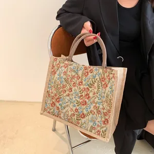 Détail d'un sac cabas en lin à motif floral vintage avec des poignées arrondies.