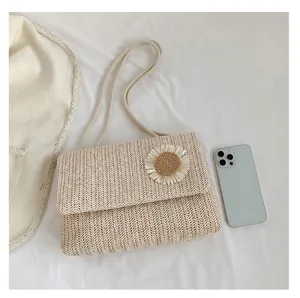 Vista detallada superior de un bolso de hombro de paja beige con una flor blanca decorativa