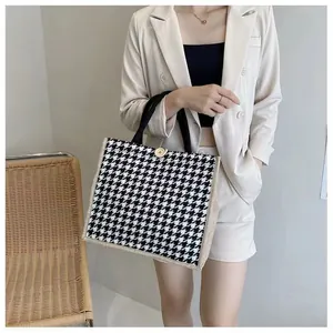 Gros plan d'un sac cabas pied-de-poule noir et blanc avec panneaux latéraux en lin.