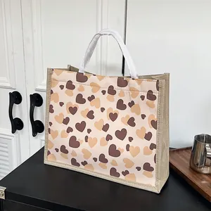 Vue détaillée du sac cabas en toile de jute avec motif cœur et poignées blanches