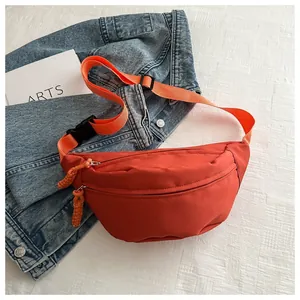 Close-up view of a casual orange nylon belt bag styled on a denim jacket background