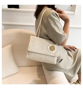 Elegante bolso de hombro de paja con detalle de girasol, llevado por una modelo con estilo