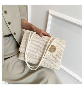 Bolso de paja tejida crema hecho a mano con adorno floral llevado por modelo