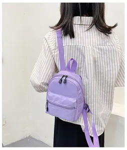 Close-up rear view of a model wearing a stylish purple nylon mini backpack for women