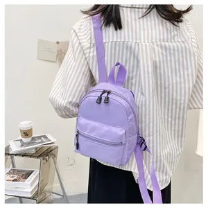 Close-up detail of a stylish light purple nylon mini backpack worn by a female model