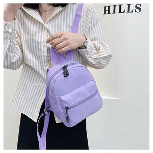 Detailed view of a light purple nylon mini backpack held by a model in a striped shirt