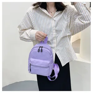 Female model holding a stylish purple nylon mini backpack for a daily casual look