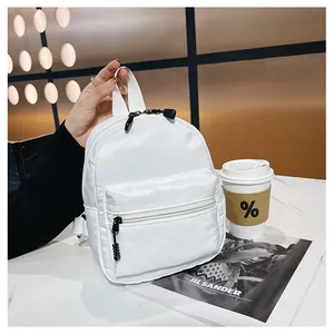 Close-up of a white nylon mini backpack placed on a table with a lifestyle magazine
