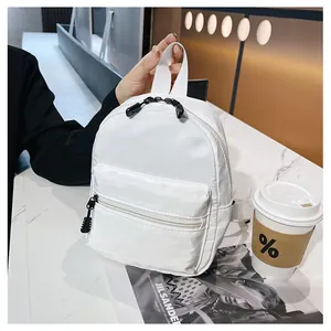 Close-up of a stylish white nylon backpack placed on a marble table with coffee and magazine