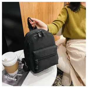 Detail of a small black nylon backpack held in a lifestyle cafe setting with coffee.