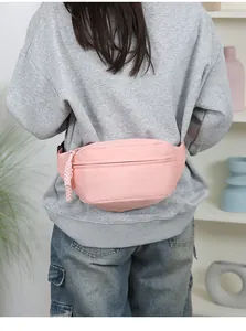 Detaillierte Rückansicht einer minimalistischen rosa Nylon-Gürteltasche auf grauem Sweatshirt.