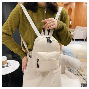 Stylish cream nylon mini backpack for women worn by a model in a cozy cafe setting