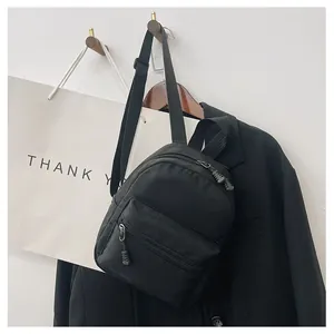Detail shot of a classic black nylon backpack hanging on a wall hook with a jacket