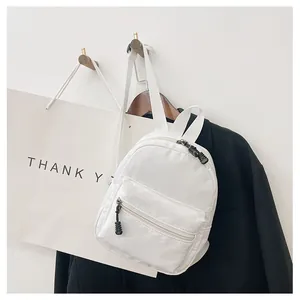 Minimalist white nylon mini backpack for women hanging in a stylish lifestyle setting