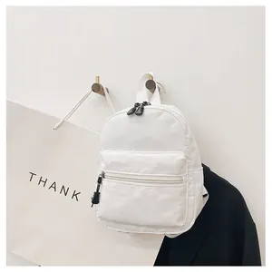 Clean aesthetic view of a small white nylon backpack hanging on a minimalist wall hook