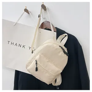 Detailed shot of a minimalist cream nylon backpack hanging on a wooden hook set