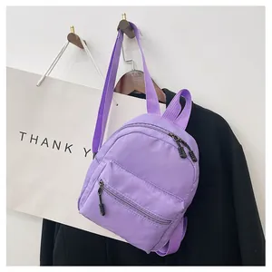 Purple minimalist nylon mini backpack hanging on a wall hook next to a black blazer