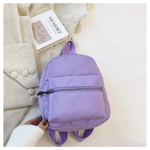 Detailed close-up view of a purple nylon mini backpack featuring a front zipper pocket