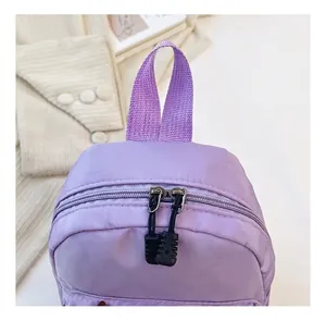 Close-up of durable purple nylon backpack featuring metal zippers and handle details.