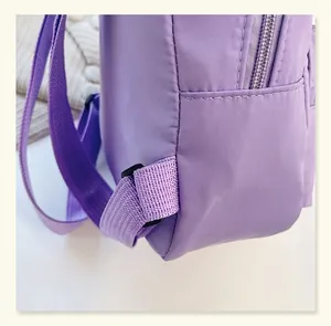 Close-up of durable purple nylon backpack stitching and shoulder strap reinforcement detail
