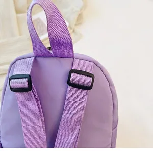 Detail view of purple nylon backpack featuring adjustable shoulder straps and buckles.