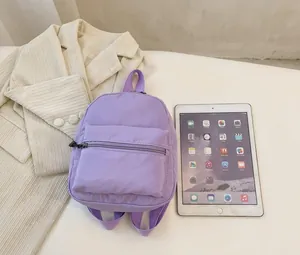 Detail view of small purple nylon backpack compared to a tablet for size reference