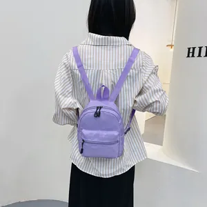 Trendy purple mini nylon backpack for women, stylish casual daypack worn over a striped shirt