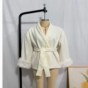 Detailed view of an elegant white belted woolen coat with luxury faux fur cuffs on a mannequin