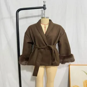 Macro view of women's brown woolen coat featuring faux fur cuffs and waist tie detail