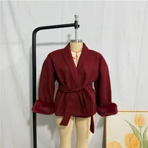 Detail view of a wine red woolen coat featuring elegant faux fur cuffs and a belted waist