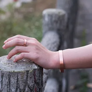 Primer plano de un conjunto de pulsera y anillo magnético de cobre puro en la mano