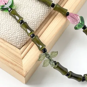 Vista macro de amuletos de bambú de vidrio verde y tulipán rosa en un cordón