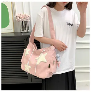 Détail d'un sac fourre-tout en velours côtelé rose avec étoiles en peluche sur un modèle