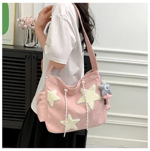 Detailed side view of pink corduroy tote bag featuring plush star patterns and a cute charm