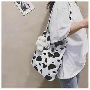 Vue détaillée du sac fourre-tout imprimé vache porté à l'épaule avec petit ours