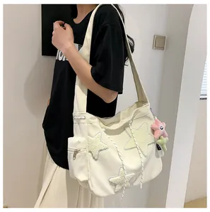Detailed shot of a large cream corduroy shoulder bag with star patches worn by a model