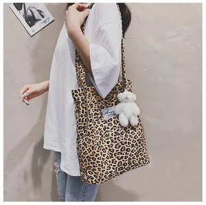 Grand sac fourre-tout à imprimé léopard avec charm ours mignon porté par un modèle