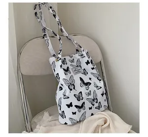 Sac cabas en toile blanche minimaliste avec imprimé papillon noir dans un décor élégant