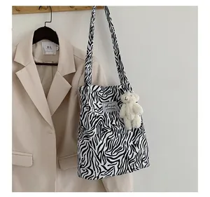 Gros plan détaillé du sac cabas en toile zébrée avec un pendentif ours blanc mignon