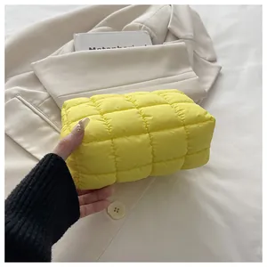 Detailaufnahme einer leuchtend gelben, gesteppten Cloud-Kosmetiktasche in einer Hand