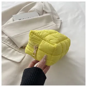 Nahaufnahme der Textur einer gelben gesteppten Kosmetiktasche, die in der Hand gehalten wird