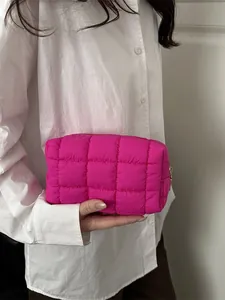 Modische gesteppte Kosmetiktasche in Pink mit quadratischem Gittermuster in der Hand