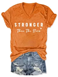 Détail du t-shirt orange pour femme à col en V avec l'inscription 'Stronger Than The Storm'.