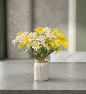 Dekorativer künstlicher Gänseblümchen-Strauß in weißer Keramikvase auf grauem Tisch