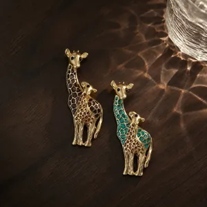 Exquisite enamel giraffe brooches detailed with gold accents on dark wood surface