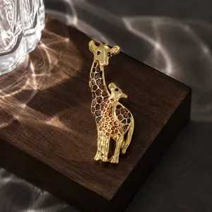 Close-up detail of an elegant gold-plated enamel giraffe brooch with warm light reflections.