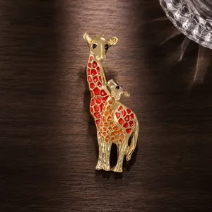 Close-up of gold enamel giraffe brooch with red and orange spots on dark wood