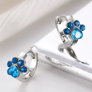 Primer plano detallado de pendientes de aro con pata de gato y cristales azules brillantes