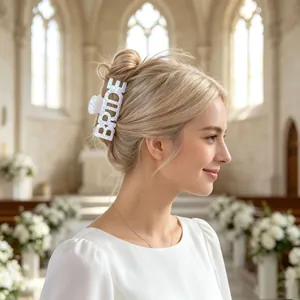 Gros plan d'une pince à cheveux "BRIDE" irisée sur une mariée blonde dans une église.
